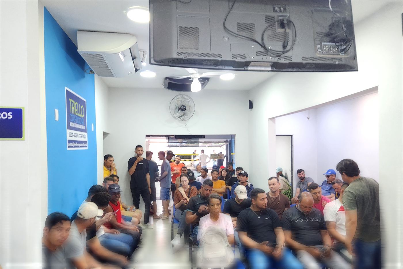 Corredor de acesso aos consultórios, com sinalização e o cartaz da Triello na parede azul.